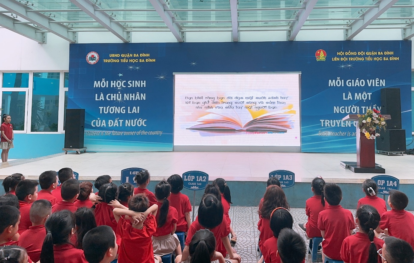 A group of children in red shirts standing in front of a screen

Description automatically generated